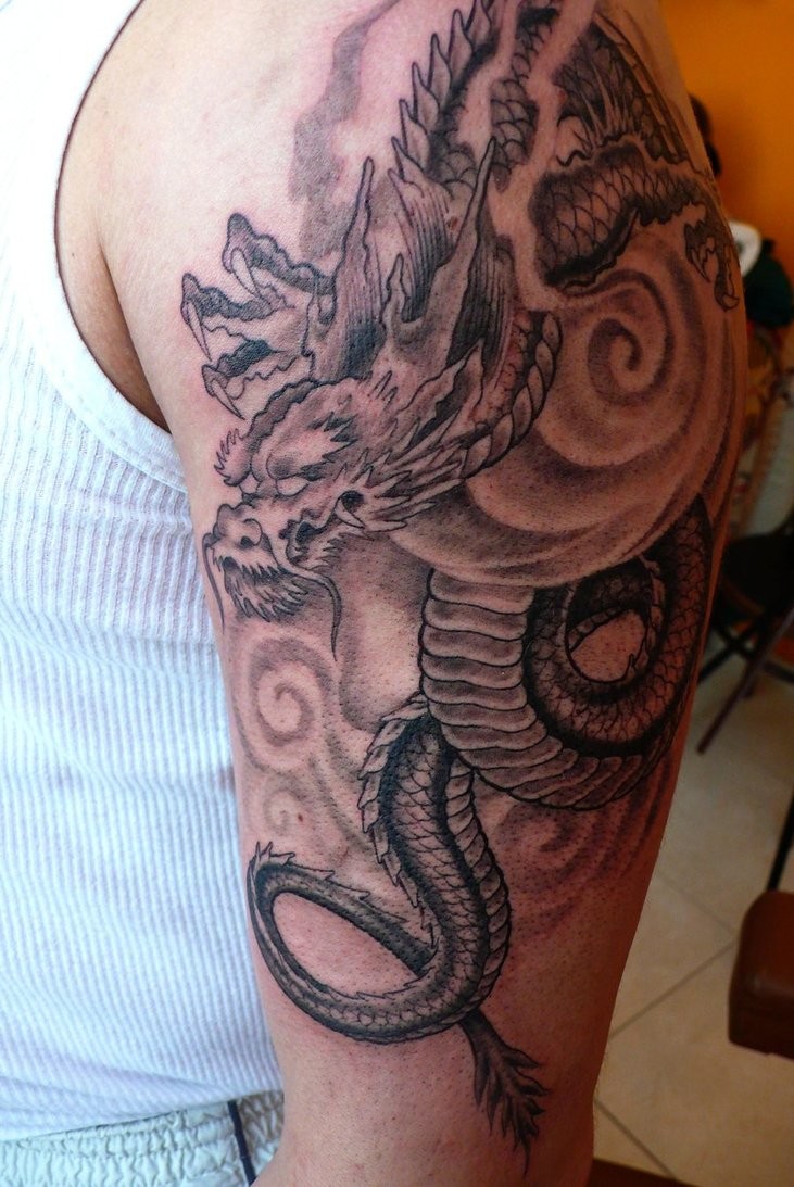 Tatuaggio nero bianco sul deltoide il dragone