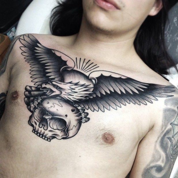 Black and gray eagle with a skull in its claws tattoo on chest