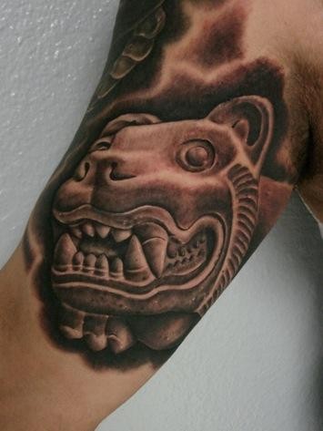 Black and gray style biceps tattoo of stone statue
