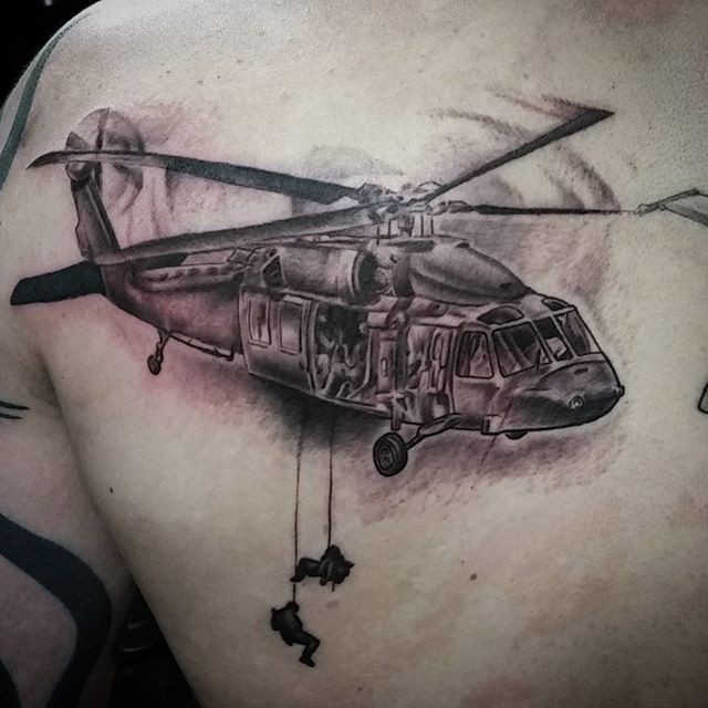 Black and gray style big detailed military helicopter with soldiers tattoo on scapular