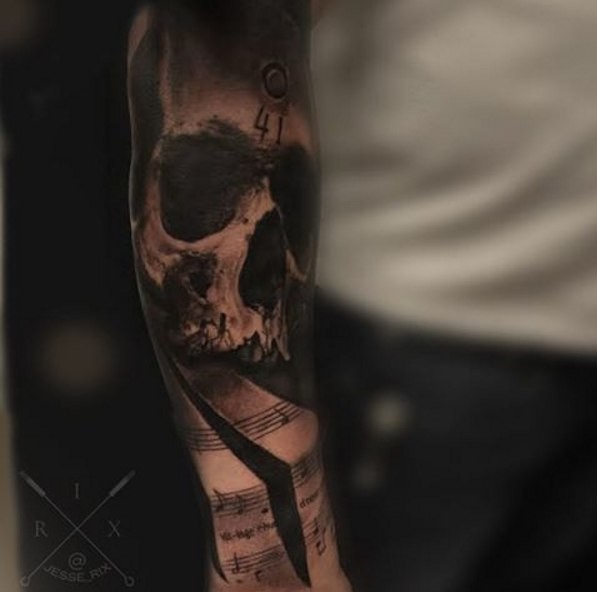 Black and gray style colored arm tattoo of human skull with music notes