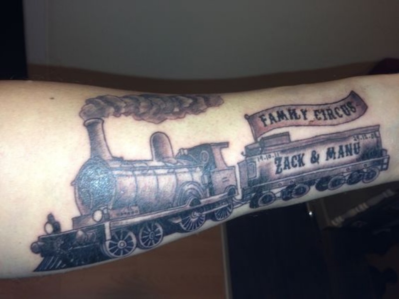 Black and gray style colored arm tattoo of large train with lettering
