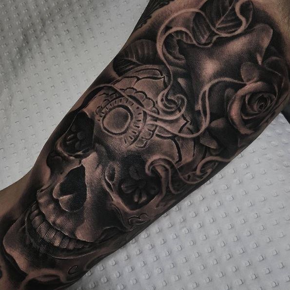 Black and gray style colored arm tattoo of human skull with rose and ornaments