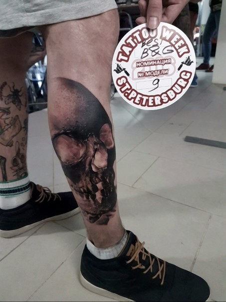Black and gray style colored leg tattoo of human skull