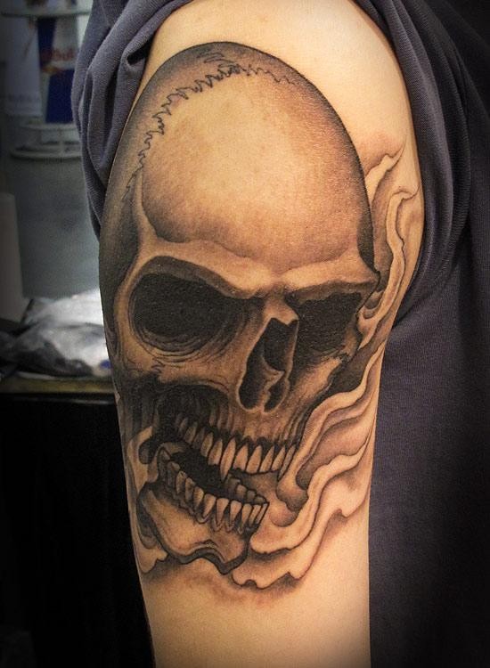 Black and gray style colored shoulder tattoo of human skull