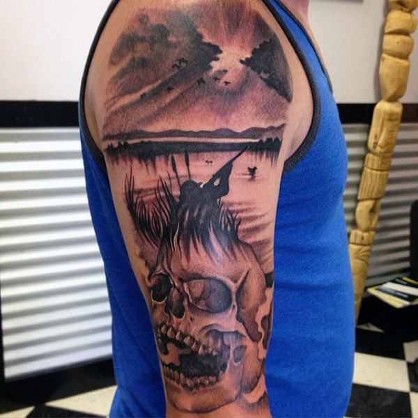 Black and gray style colored shoulder tattoo of hunter with skull