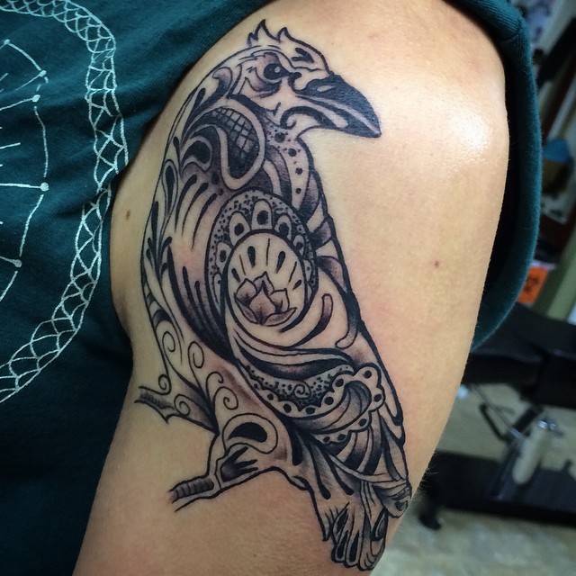 Black and gray style colored shoulder tattoo of bird stylized with ornaments