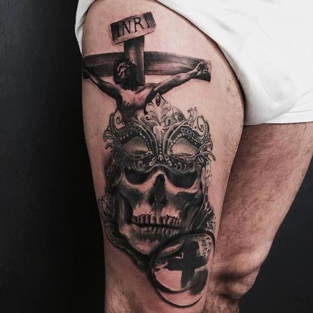 Black and gray style colored thigh tattoo of Jesus on cross with skull and mask