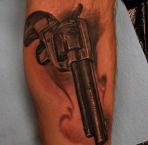 Black and gray style colored very detailed western pistol tattoo on forearm