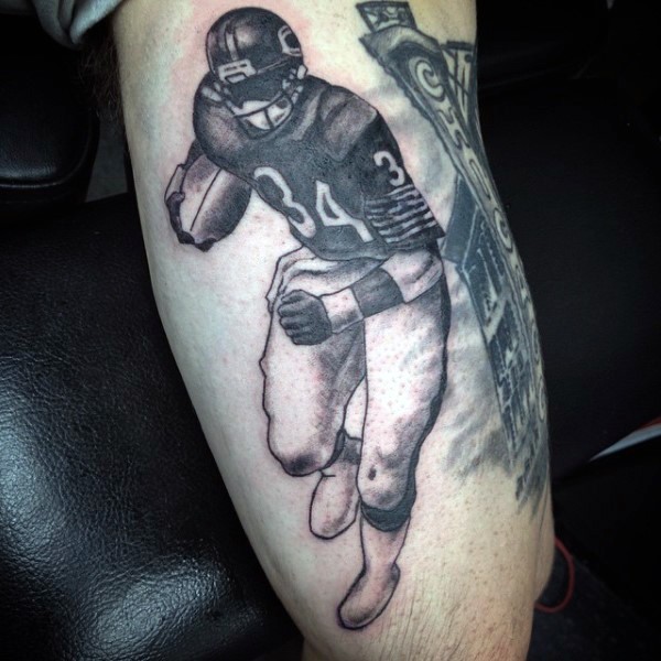 Black and gray style detailed biceps tattoo of American football player