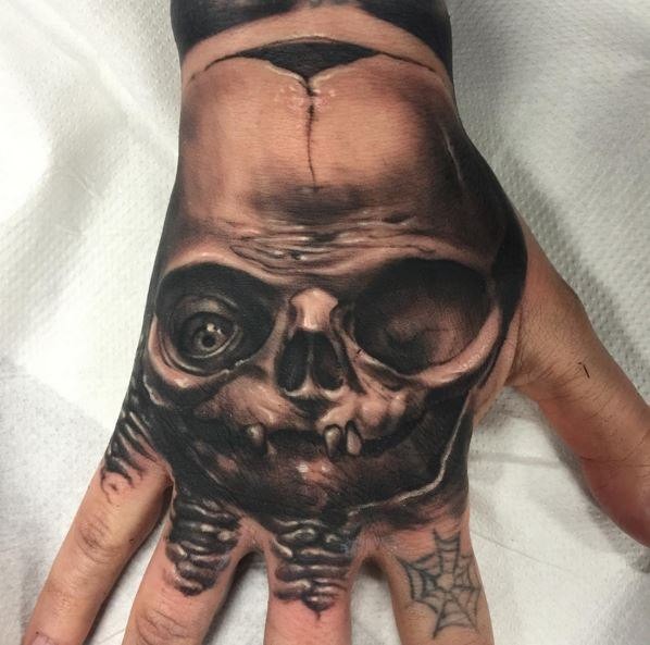 Black and gray style detailed hand tattoo of monster skull with eye