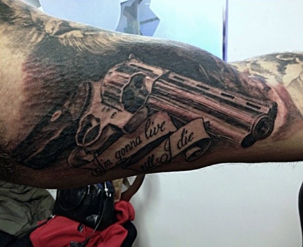 Black and gray style detailed looking biceps tattoo of great revolver and lettering