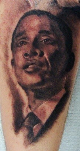 Black and gray style detailed young Obama face tattoo on leg
