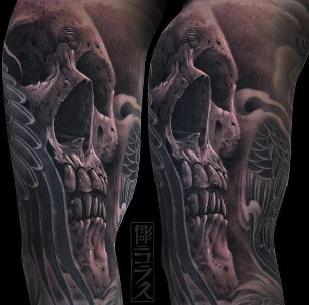 Black and gray style mystical looking arm tattoo of human skull stylized with angel wings