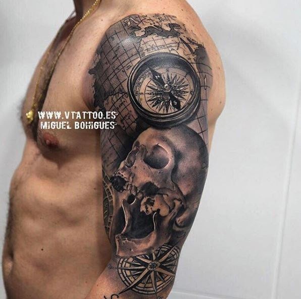 Black and gray style shoulder tattoo of human skull with compass and map