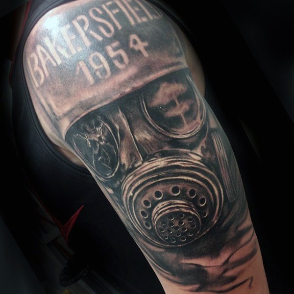 Black and gray style shoulder tattoo of corrupted gas mask and lettering