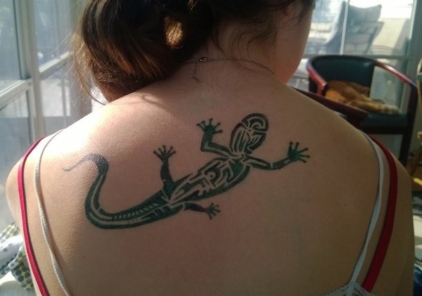 Black and white designed medium size lizard tattoo on girl's upper back