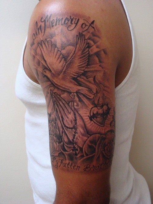 Black-and-white dove with sun and lettering tattoo on upper arm