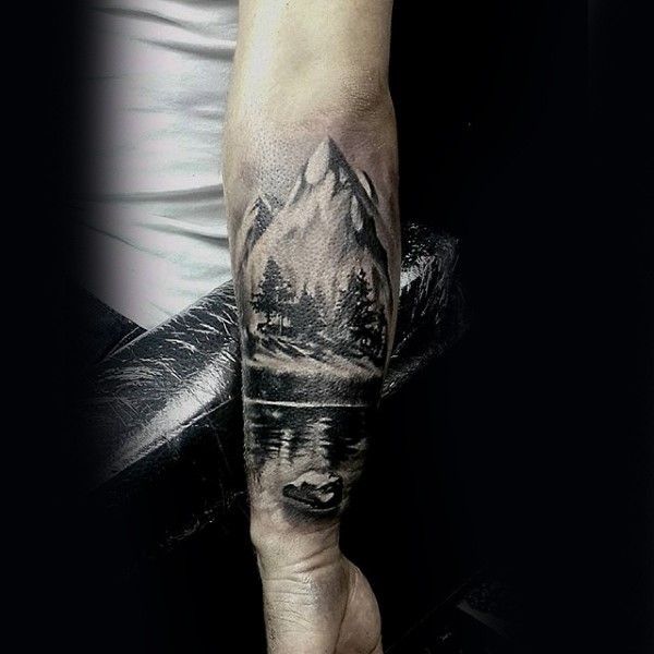 Black and white forearm tattoo of mountains with forest and lake