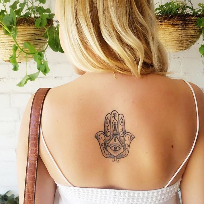 Black and white medium size Hamesh hand tattoo on woman's center back