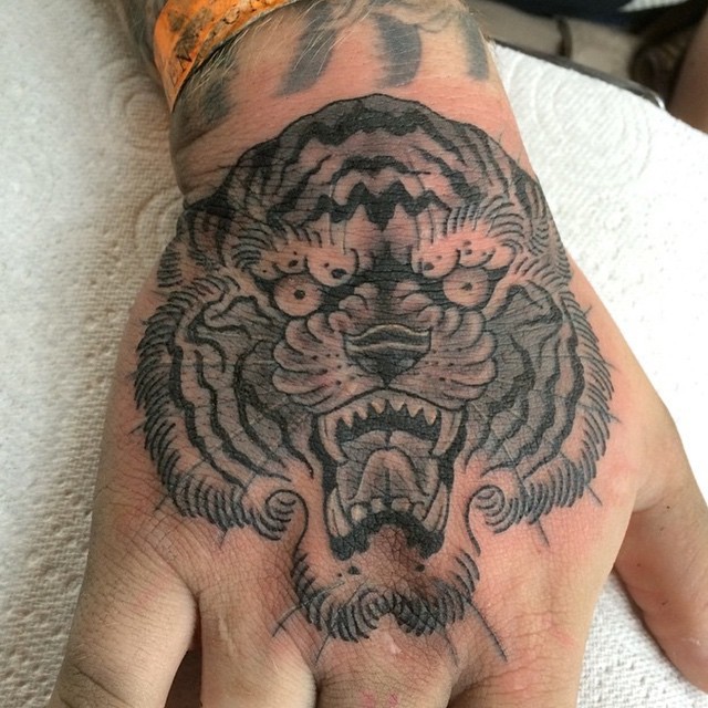 Black and white old school roaring tiger's head hand tattoo