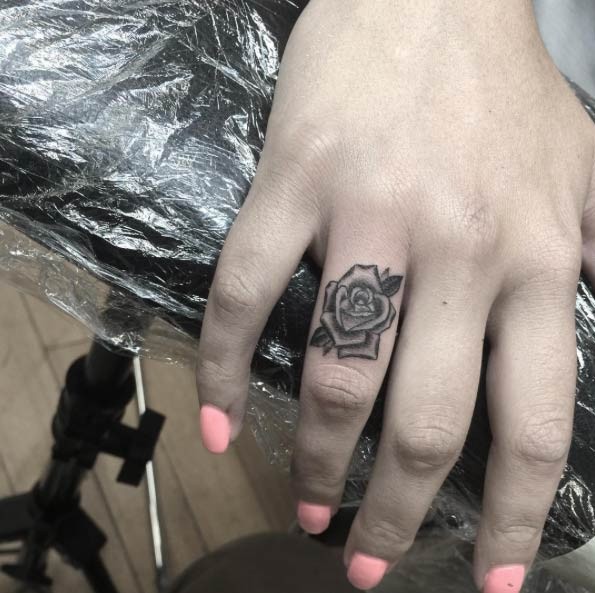 Black and white rose flower detailed tattoo on ring finger