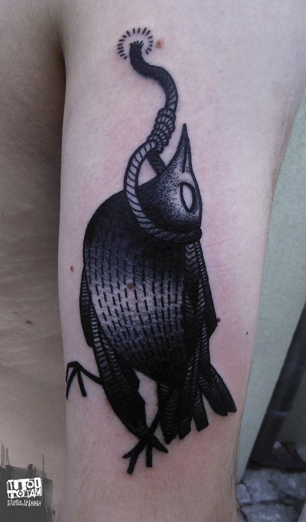 Black and white shoulder tattoo of crow hanging on arm