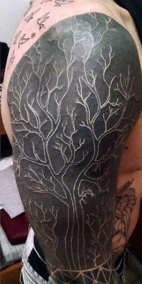 Tatuaje en el brazo, árbol grande excelente en el fonde negro