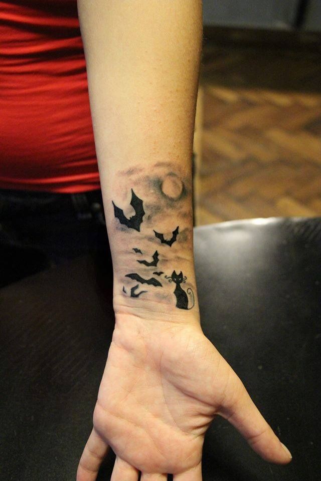 Black cat and flying bats at night tattoo on wrist