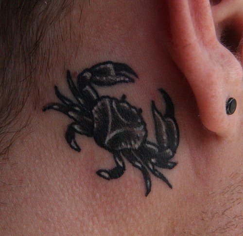 Black crab tattoo behind ear for lady