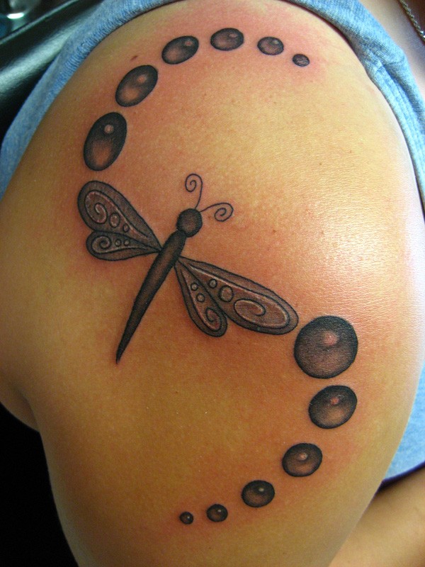 Black dragonfly tattoo on shoulder
