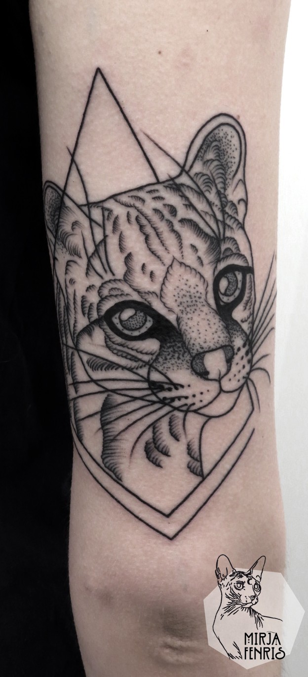 Black ink arm tattoo of cat face with ornaments