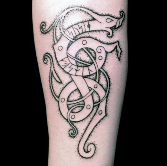 Black ink arm tattoo of creepy looking ornament with lettering