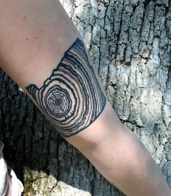 Black ink arm tattoo of crossed section of the tree