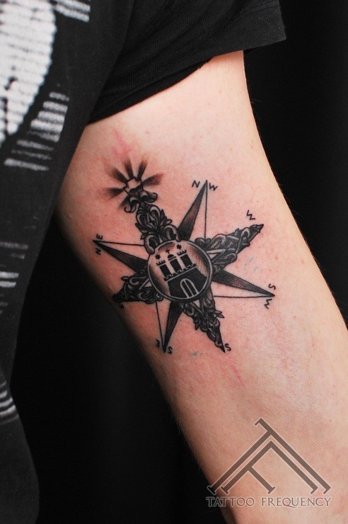 Black ink arm tattoo of nautical star stylized with castle