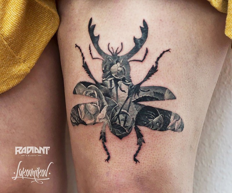 Black ink awesome looking thigh tattoo of large bug stylized with roses