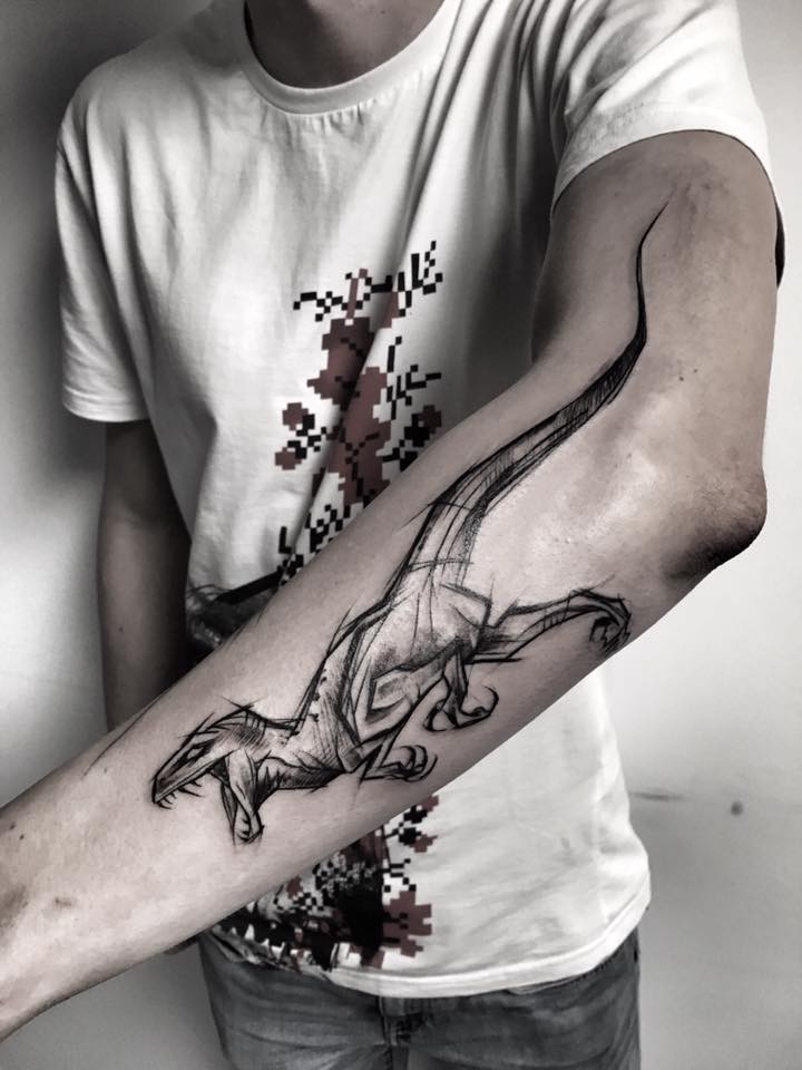 Tinta preta grande pintada por Inez Janiak braço tatuagem de dinossauro em execução