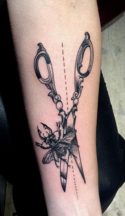 Tatuaje en el brazo, tijeras y insecto, color negro