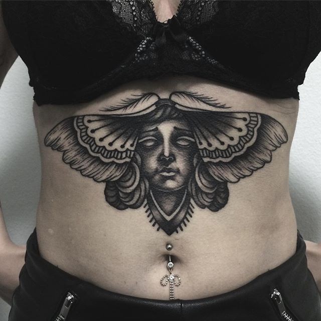 Black ink butterfly with human face tattoo on belly