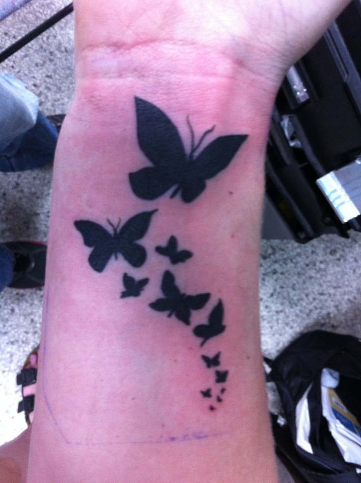 Tatuaje  de bandada de mariposas negras en la muñeca