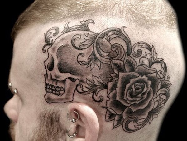 Black ink cartoon style head tattoo of humans skull with rose