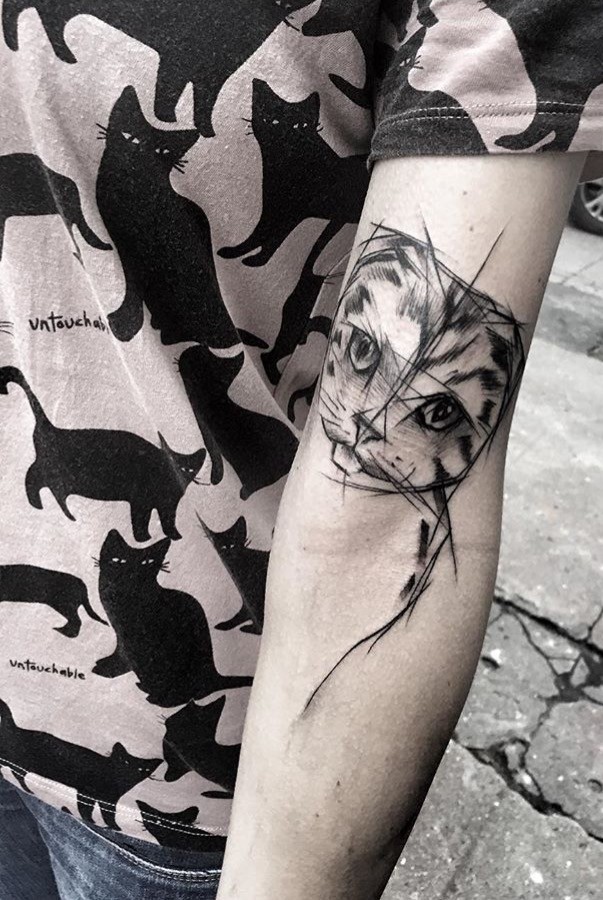 Tatuagem de tatuagem de gato tinta preta desenhada por Inez Janiak no bíceps