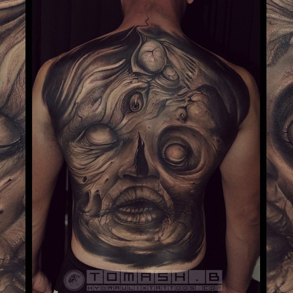 Black ink detailed looking whole back tattoo of mysterious monster face