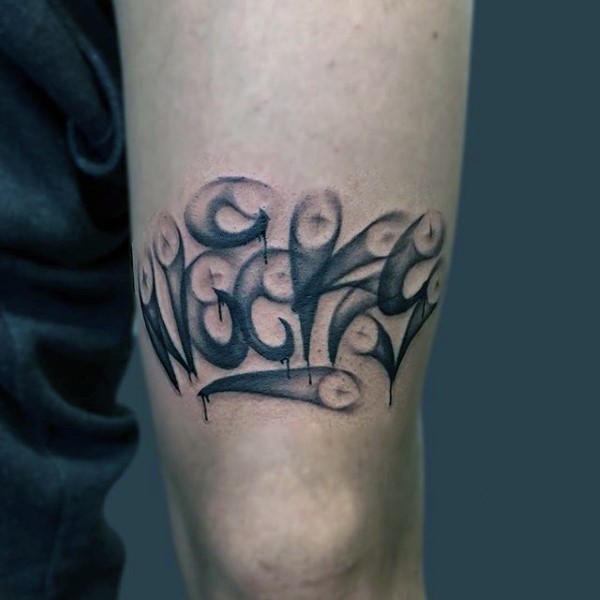Black ink elbow tattoo of small graffiti lettering