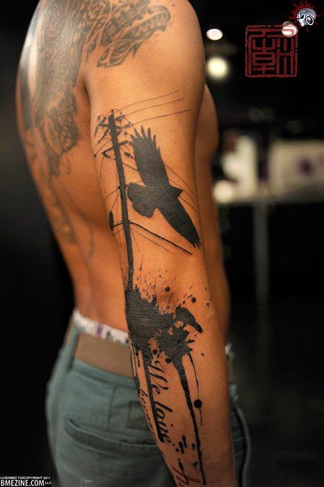 Black ink flying crow in city tattoo on sleeve with lettering