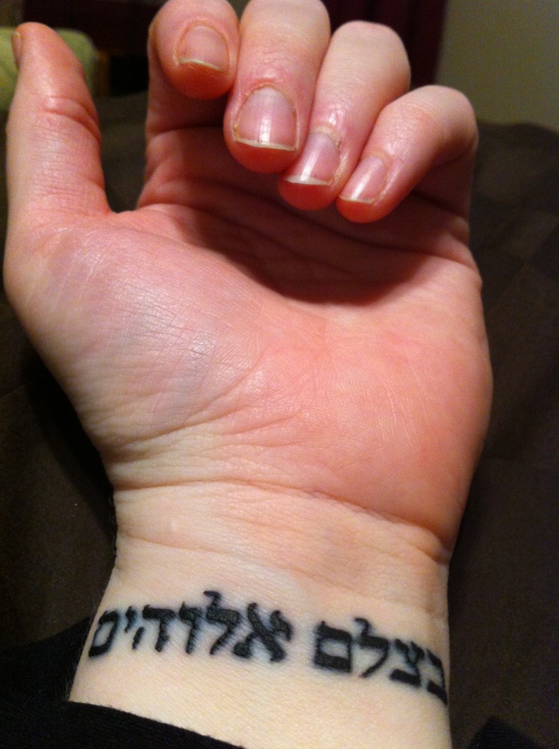 Schwarze Tinte hebräisches Tattoo am Handgelenk