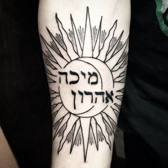 Black ink impressive sun with Hebrew lettering inside forearm tattoo