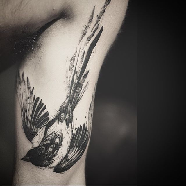 Black ink interesting looking arm tattoo of bird