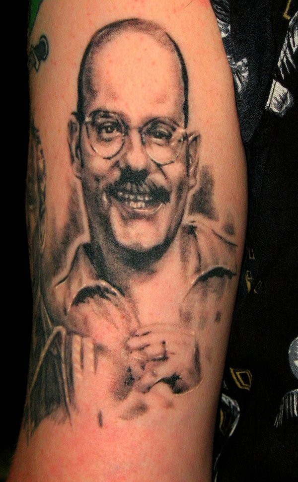 Tatuaje en el brazo, hombre sonriente en gafas