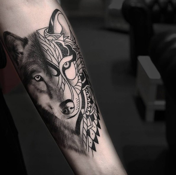 Tinta negra con bonito tatuaje en el antebrazo de medio retrato de lobo mitad medio realista